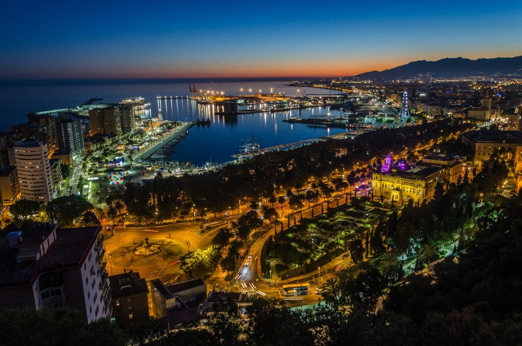 Night aerial view of Málaga’s waterfront and port, illuminated promenade and Muelle Uno seen from above, highlighting the central coastal area ideal for a first stay