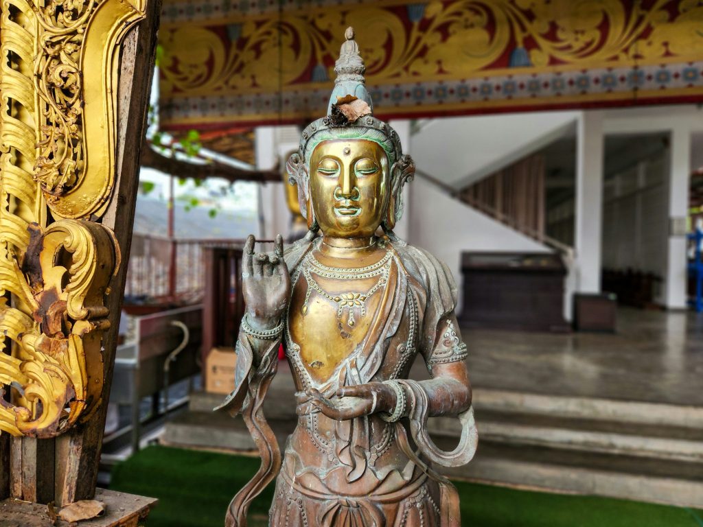 Large seated Buddha statue overlooking the ocean and tropical coastline in Sri Lanka